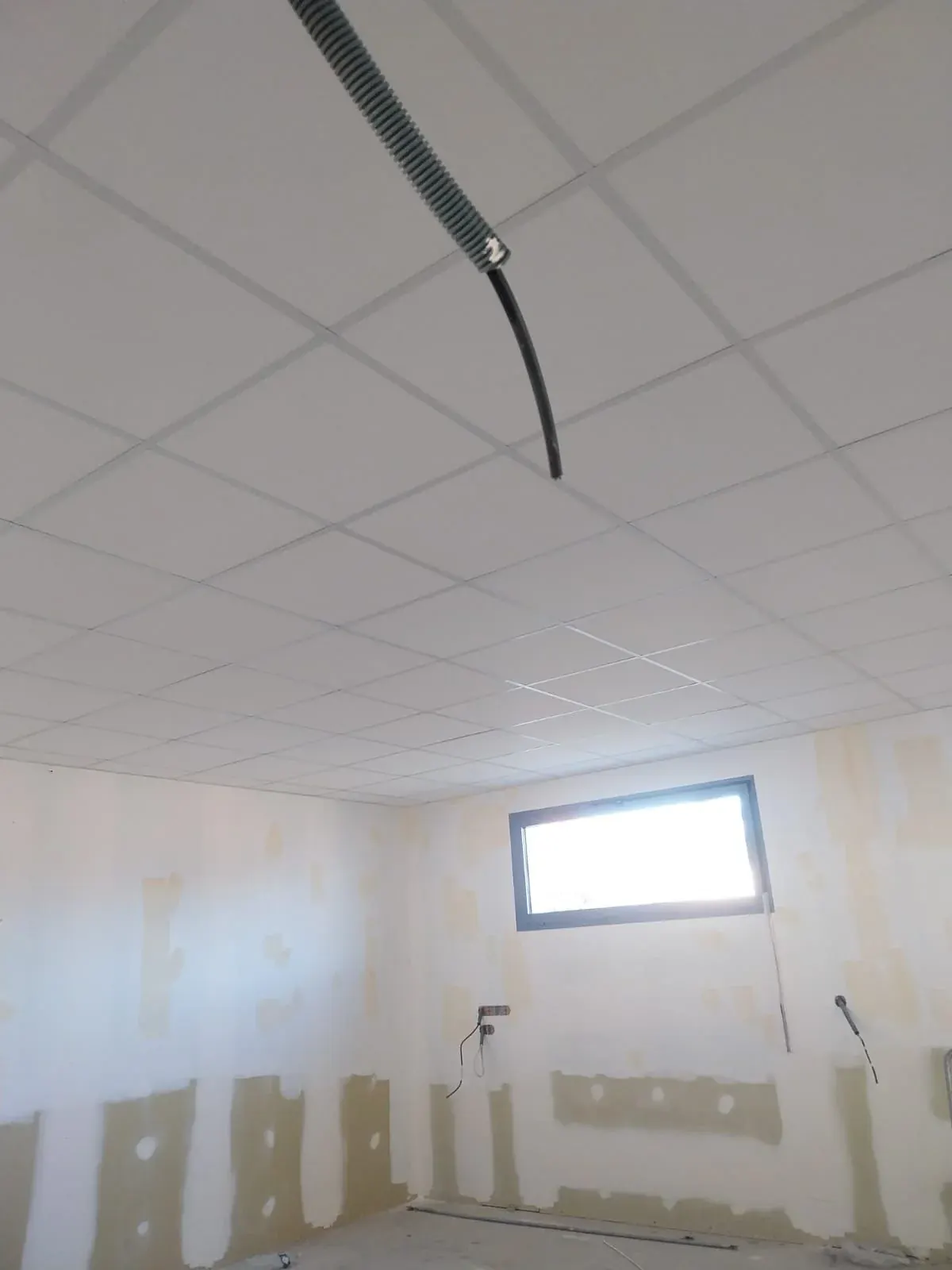 Attente électrique descendue à travers un faux plafond en dalles